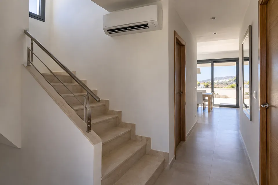 Aire acondicionado junto a una escalera interior de una casa de dos plantas