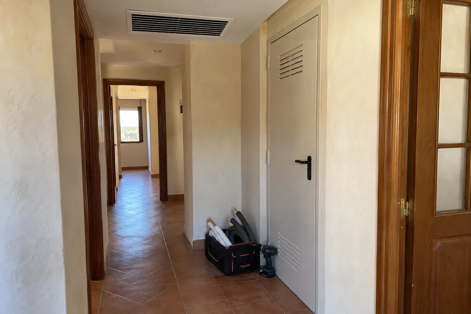 Rejilla de climatización en el techo de un pasillo con herramientas de montaje